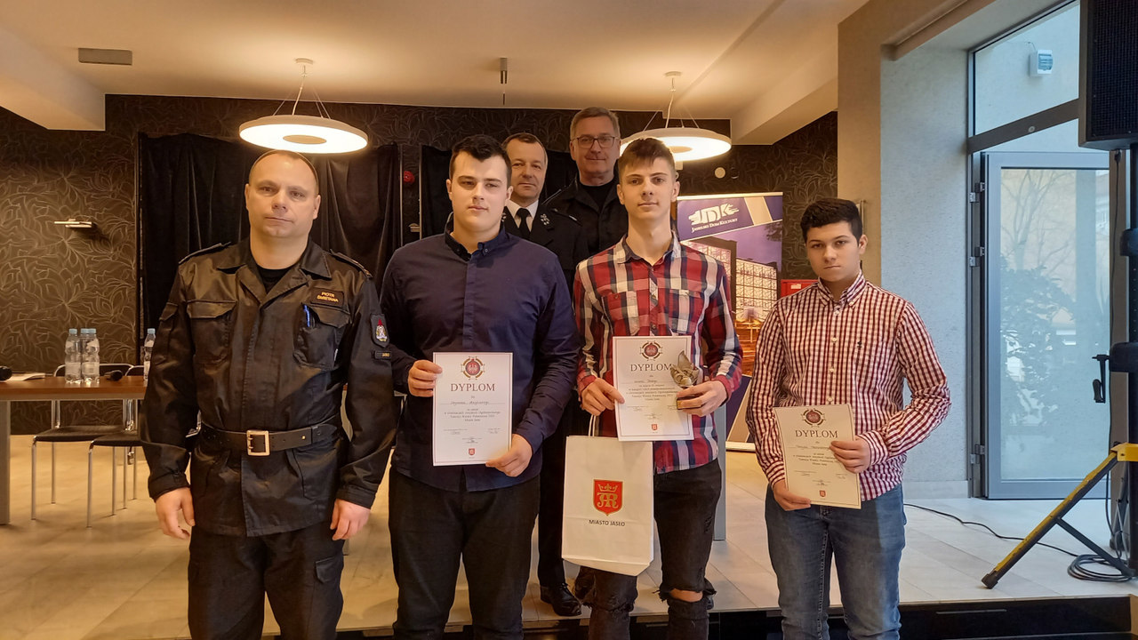 Na zdjęciu trzech uczniów z dyplomami oraz z przedstawicielami Powiatowej Państwowej Straży Pożarnej w Jaśle