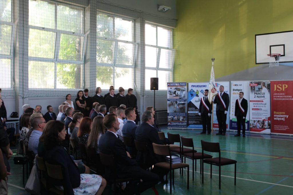 Nauczyciele, zaproszeni goście, Poczet Sztandarowy oraz przedstawiciele chóru szkolnego zgromadzeni w sali gimnastycznej Zespołu