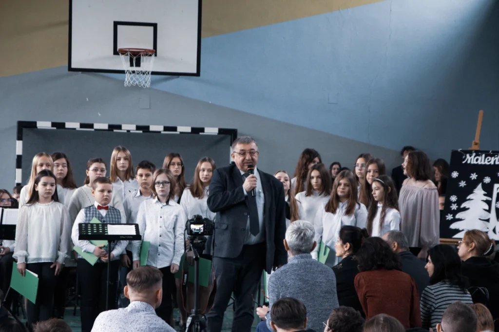 Dyrektor ZST w Jaśle przemawiający na tle dziecięcego chóru