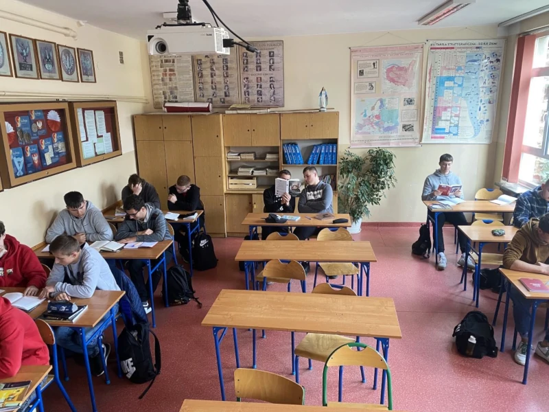 Uczniowie siedzący w sali lekcyjnej i czytający książki