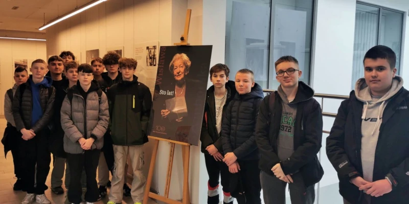 Uczniowie w korytarzu biblioteki razem z plakatem Wisławy Szymborskiej